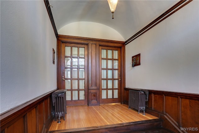 unfurnished office with french doors, hardwood / wood-style flooring, vaulted ceiling, and radiator