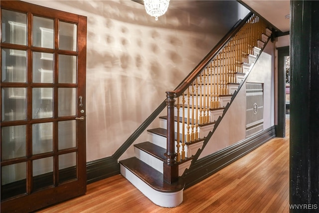 stairway with hardwood / wood-style floors and a notable chandelier