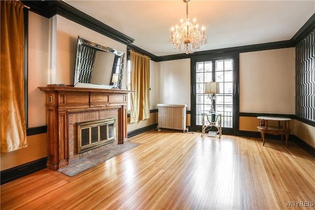 unfurnished living room featuring radiator heating unit, light hardwood / wood-style floors, crown molding, and a notable chandelier