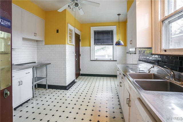 kitchen with white cabinetry, sink, ceiling fan, stainless steel counters, and pendant lighting