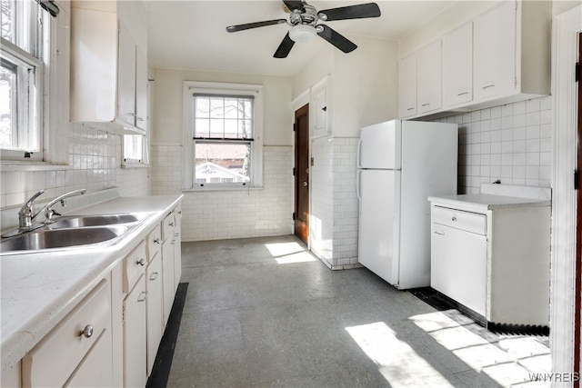 kitchen featuring white cabinets, ceiling fan, white fridge, and sink