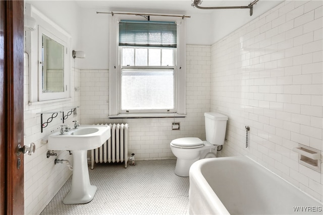 bathroom featuring tile patterned floors, a bathtub, radiator heating unit, and tile walls