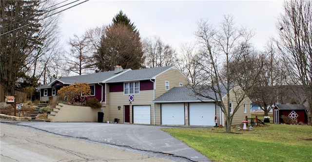 view of front facade with a front yard, a garage, and a storage shed