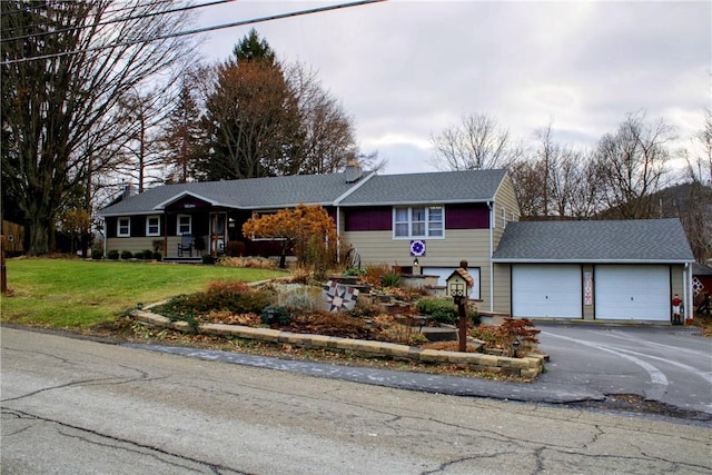 ranch-style home featuring aphalt driveway, a garage, and a front lawn