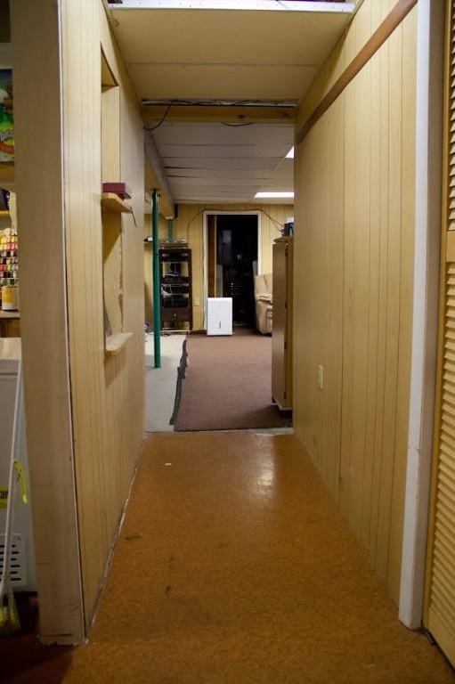 hallway featuring light colored carpet and wood walls