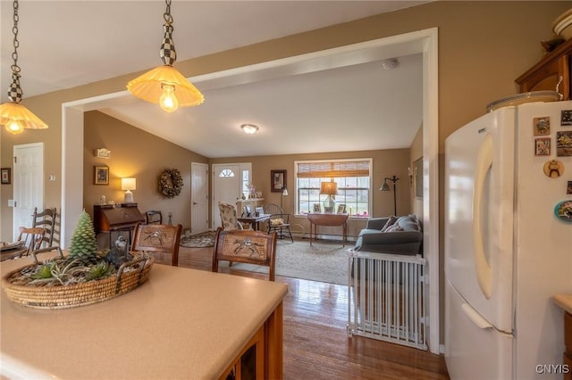 kitchen featuring pendant lighting, white refrigerator, dark hardwood / wood-style floors, and vaulted ceiling