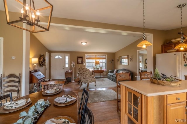 dining space with hardwood / wood-style floors, a notable chandelier, and vaulted ceiling