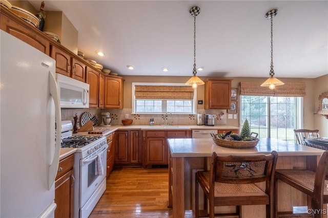 kitchen featuring a kitchen island, white appliances, light hardwood / wood-style flooring, and a healthy amount of sunlight