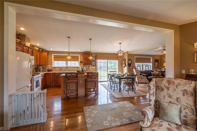 kitchen with dark hardwood / wood-style flooring, backsplash, a kitchen bar, a kitchen island, and ceiling fan with notable chandelier