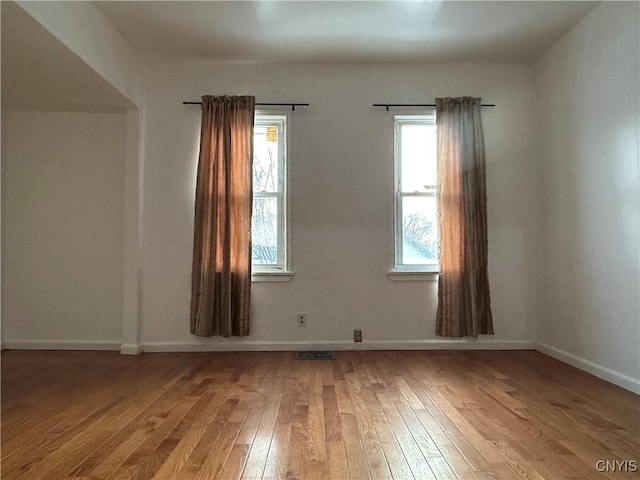 unfurnished room with hardwood / wood-style flooring and a healthy amount of sunlight