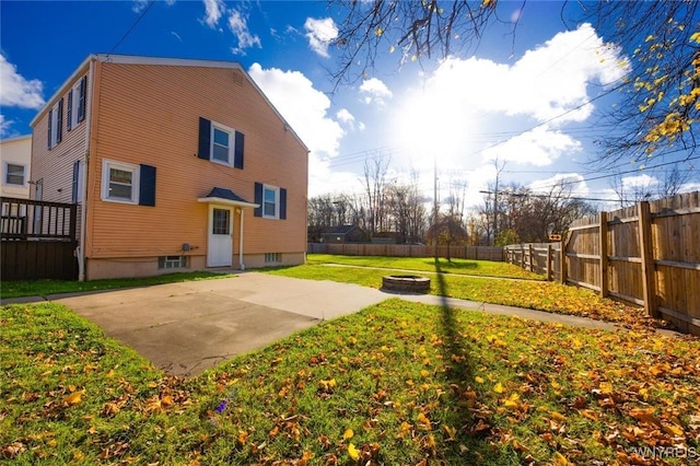 rear view of house featuring a yard, a patio, and an outdoor fire pit