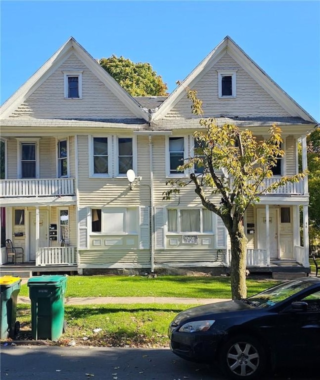 view of front of house featuring a balcony, a front lawn, and a porch