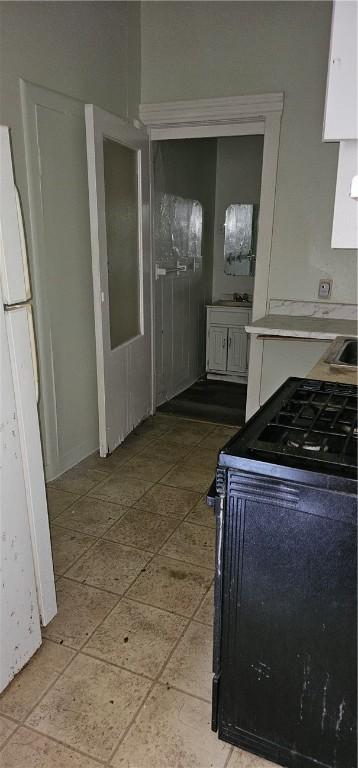 kitchen featuring white cabinetry, black electric range oven, and white fridge