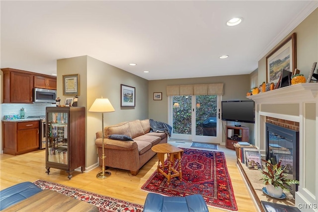 living room featuring a fireplace, light hardwood / wood-style floors, and crown molding