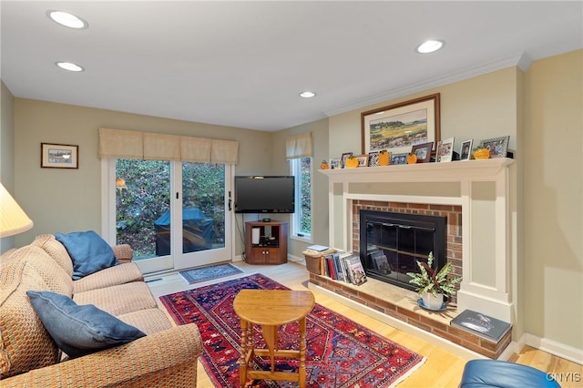 living room featuring crown molding, a fireplace, and light hardwood / wood-style flooring