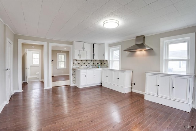 kitchen with white cabinetry, wall chimney range hood, dark wood-type flooring, and tasteful backsplash