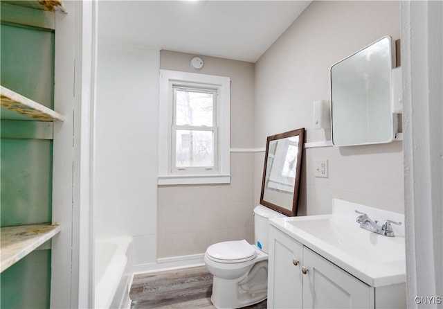 bathroom featuring vanity, hardwood / wood-style flooring, toilet, tile walls, and a tub