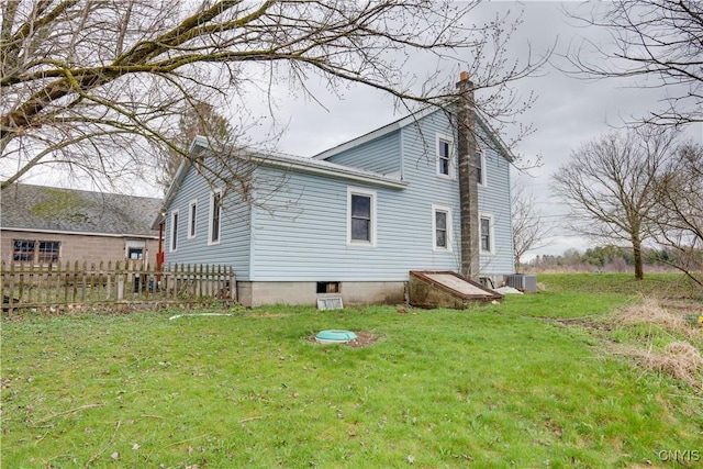 back of house with central AC unit and a lawn