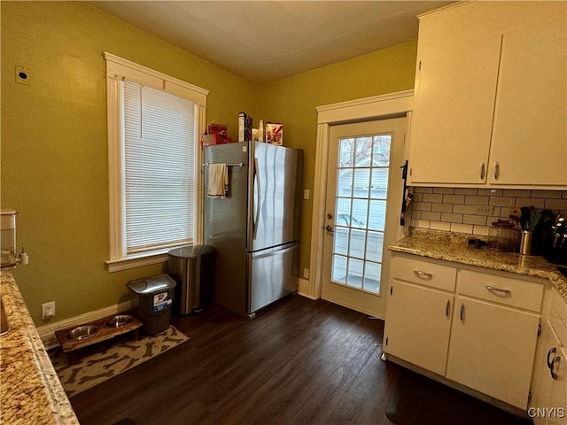 kitchen with light stone countertops, dark hardwood / wood-style floors, backsplash, stainless steel fridge, and white cabinets