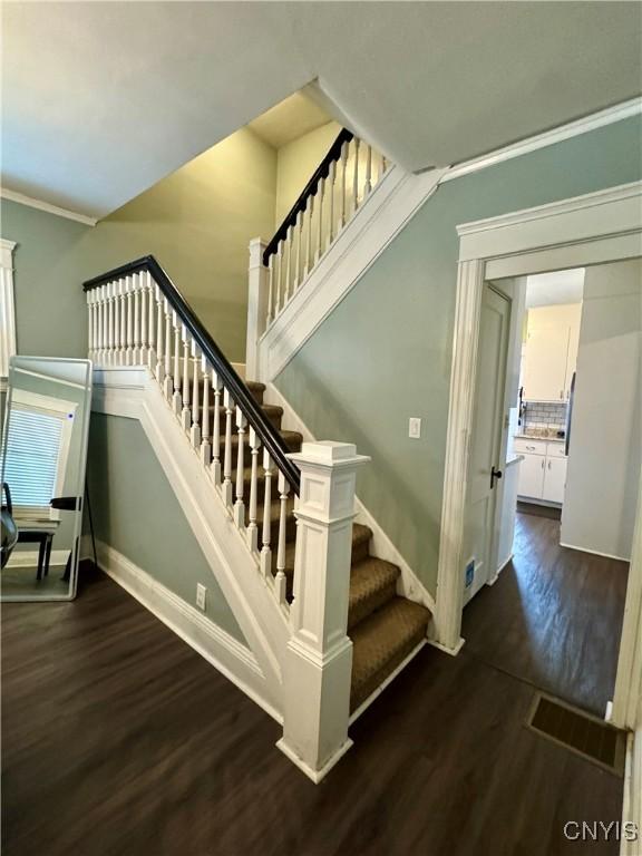 stairway with hardwood / wood-style flooring and ornamental molding