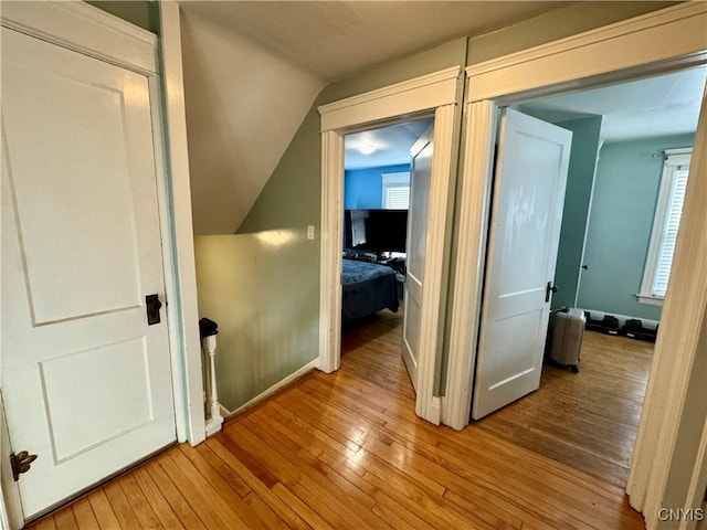 hallway featuring light wood-type flooring and vaulted ceiling