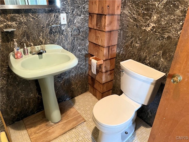 bathroom featuring tile patterned flooring, toilet, and tile walls