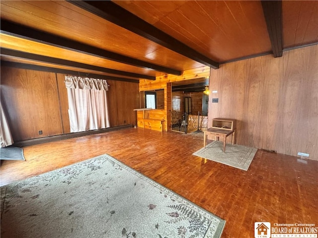 unfurnished living room with wooden ceiling, beamed ceiling, hardwood / wood-style floors, and wooden walls