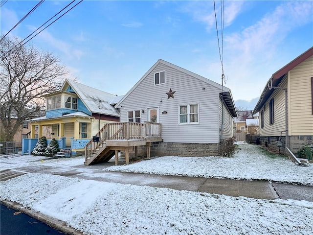 snow covered rear of property with a porch and a deck