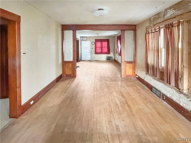 hall featuring light hardwood / wood-style flooring, a healthy amount of sunlight, and a wall unit AC