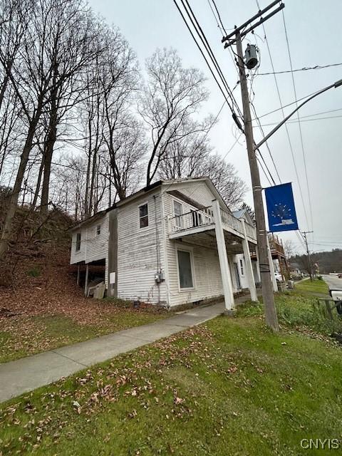 view of property exterior with a balcony and a lawn