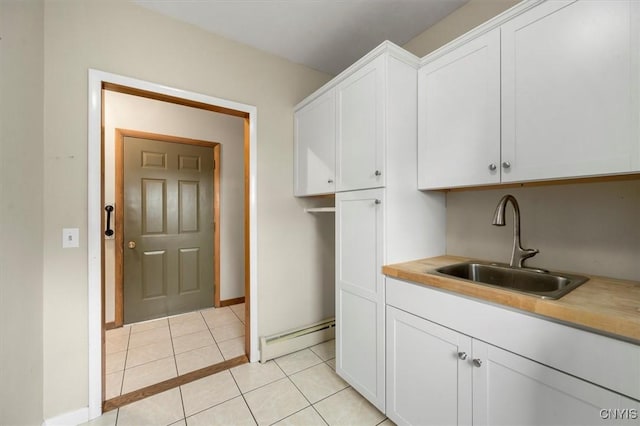 kitchen with white cabinets, light tile patterned flooring, baseboard heating, and sink