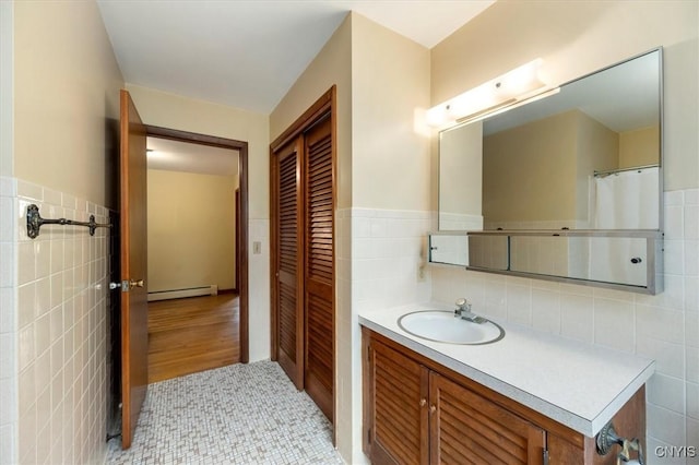 bathroom with vanity, a baseboard radiator, tile walls, and hardwood / wood-style flooring