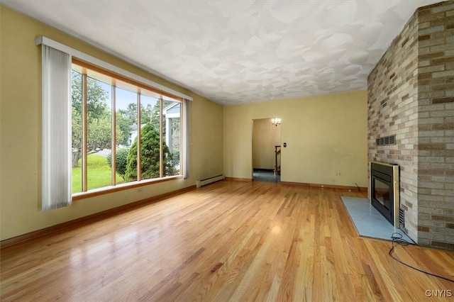 unfurnished living room featuring a fireplace, light hardwood / wood-style flooring, and a baseboard heating unit