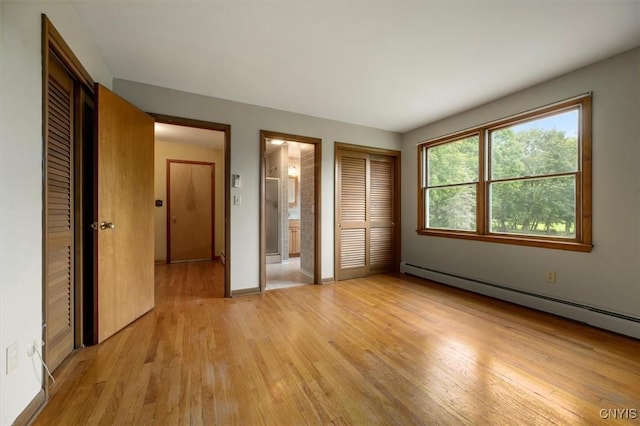 unfurnished bedroom featuring light wood-type flooring, ensuite bath, and a baseboard heating unit