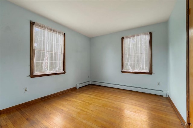 unfurnished room featuring baseboard heating and light hardwood / wood-style flooring