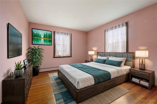 bedroom featuring baseboard heating and light hardwood / wood-style floors