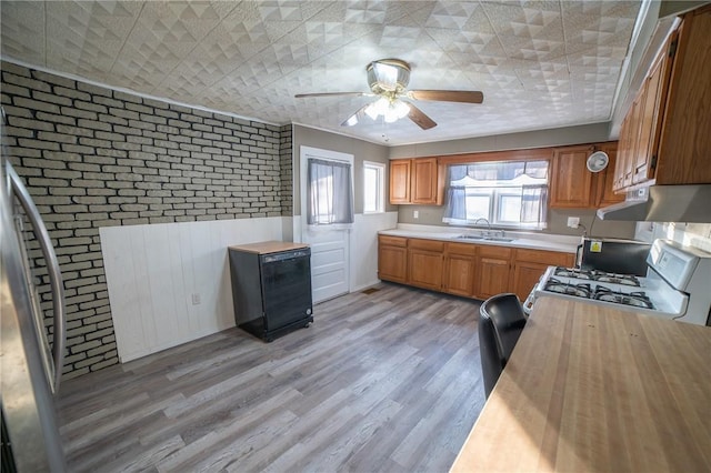 kitchen featuring brick wall, sink, light hardwood / wood-style flooring, and white gas range oven