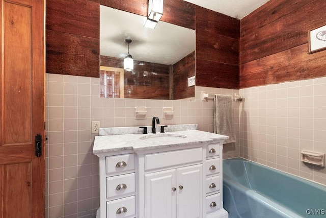 bathroom with vanity, a tub to relax in, and tile walls