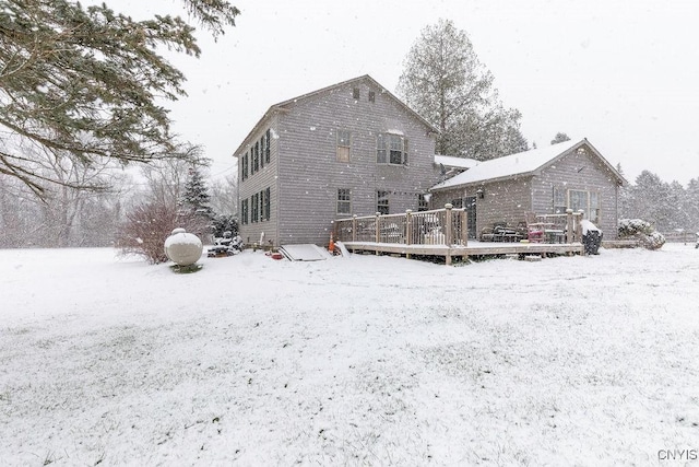 snow covered back of property featuring a wooden deck