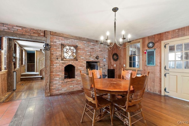 dining area featuring a chandelier, wooden walls, and dark wood-type flooring