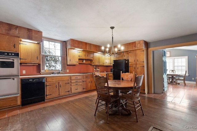 kitchen with dark hardwood / wood-style flooring, decorative light fixtures, a notable chandelier, and black appliances