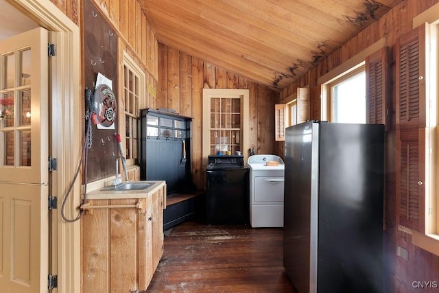 kitchen featuring sink, dark hardwood / wood-style flooring, washer / clothes dryer, vaulted ceiling, and wooden walls