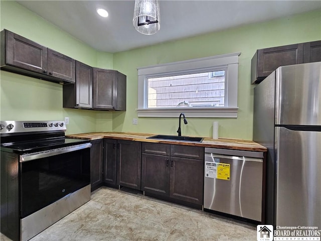 kitchen with wood counters, dark brown cabinetry, sink, and appliances with stainless steel finishes