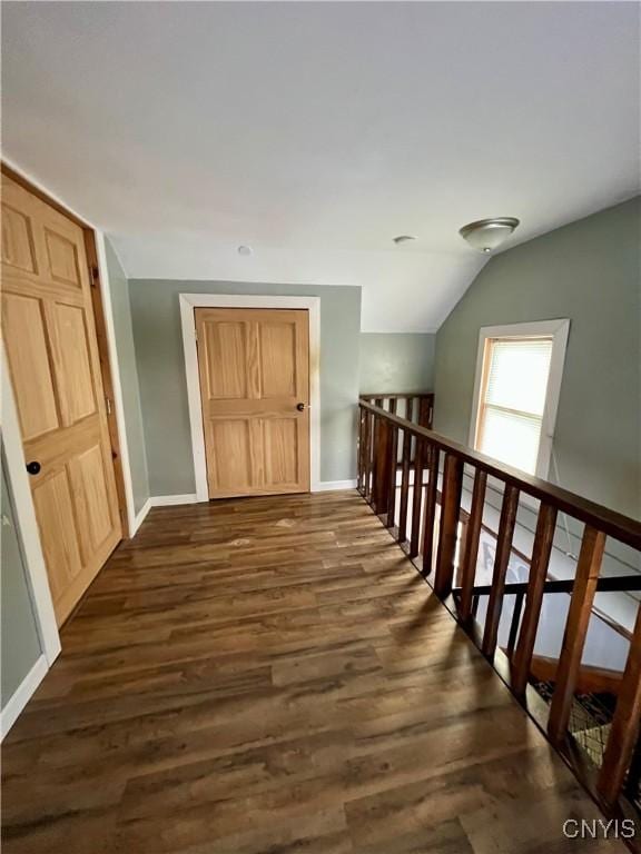 hallway with dark hardwood / wood-style floors and lofted ceiling