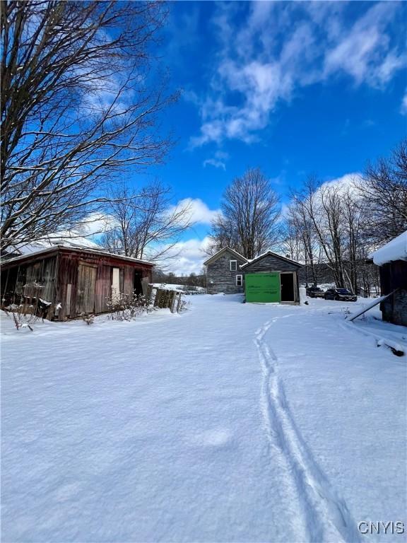 yard layered in snow featuring a garage and an outdoor structure