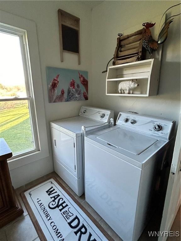 washroom featuring plenty of natural light, light tile patterned floors, and washer and clothes dryer