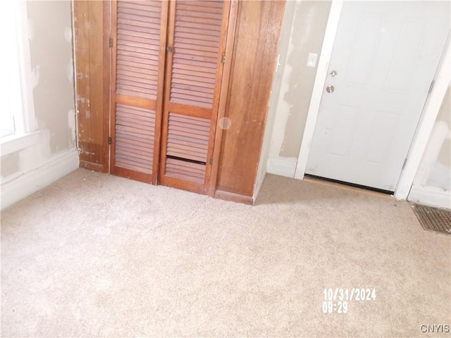 unfurnished bedroom with light colored carpet and a closet