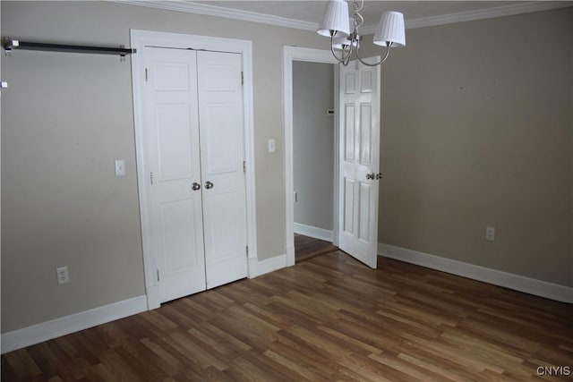 unfurnished bedroom with a chandelier, crown molding, a closet, and dark wood-type flooring