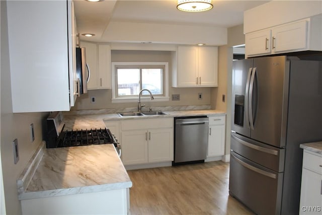 kitchen featuring light wood-type flooring, stainless steel appliances, white cabinetry, and sink