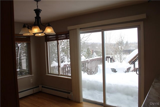 doorway with baseboard heating, hardwood / wood-style floors, and a notable chandelier